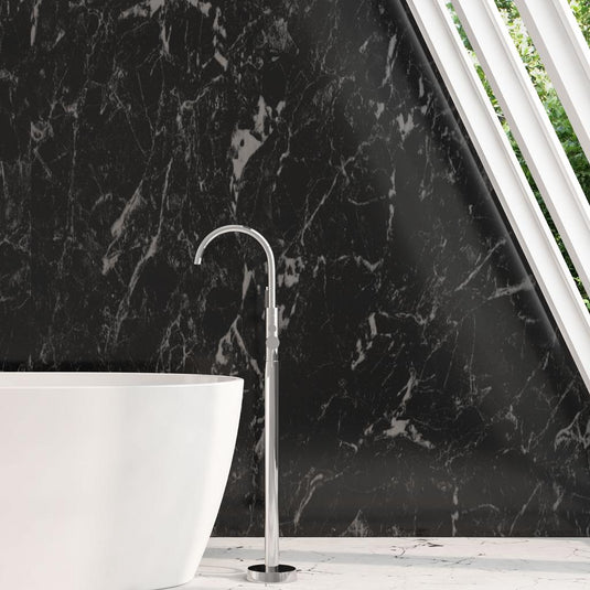 Modern freestanding chrome bath tap next to white bathtub against black marble wall