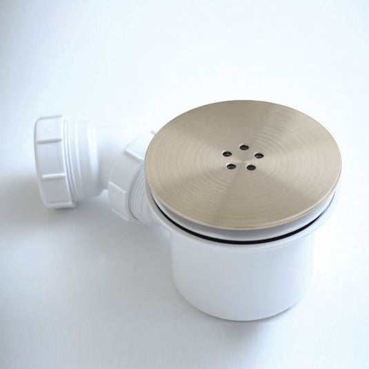 Brushed brass shower waste trap with round drain cover and white plastic outlet