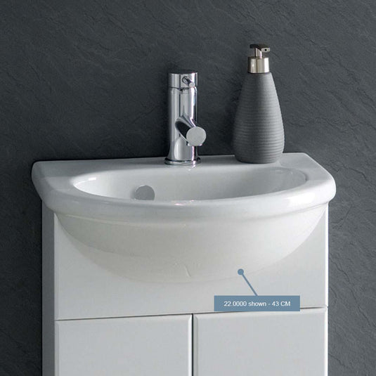 Modern white compact bathroom basin with chrome tap and grey soap dispenser on vanity unit