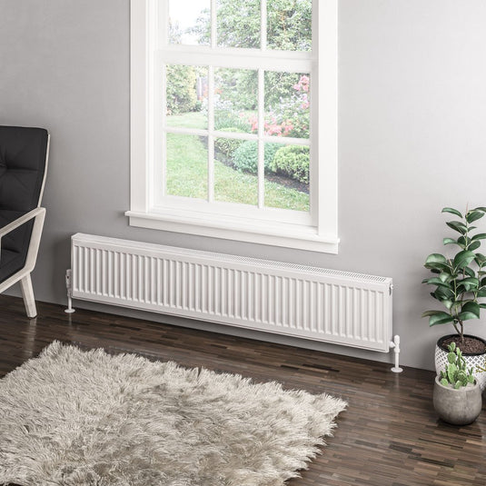 Modern white horizontal radiator installed below window in contemporary living room