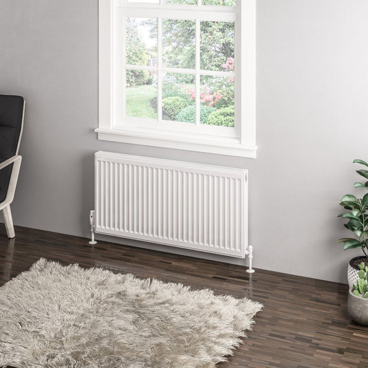 Modern white horizontal radiator under window in contemporary living room with wood flooring and rug