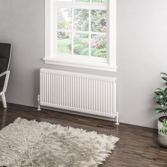 Modern white panel radiator under window in contemporary living room with grey rug and plants