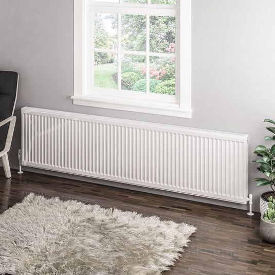 Modern white horizontal radiator under window in a contemporary living room with gray rug