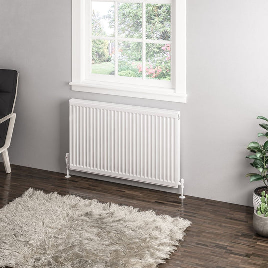 Modern white panel radiator under window in contemporary living room with shaggy rug and indoor plants.