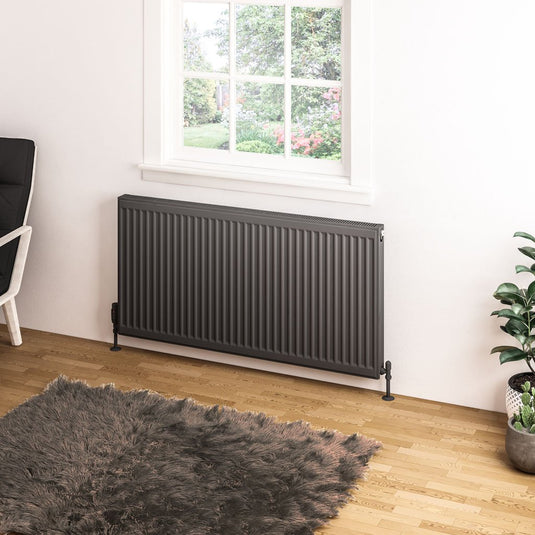 Modern horizontal anthracite radiator under window in contemporary living room with wood floor