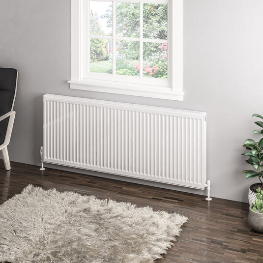 Modern white horizontal radiator under a window in a stylish bathroom with wooden floor