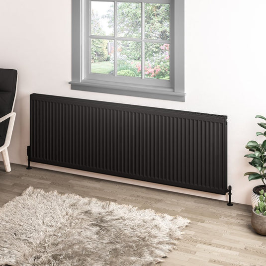 Black horizontal central heating radiator beneath window in modern living room