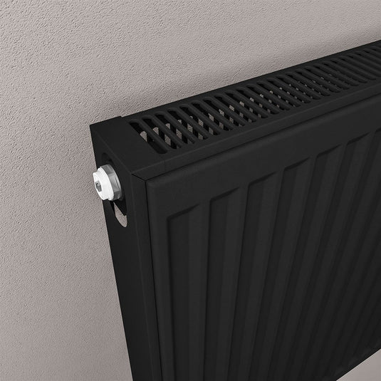 Modern black bathroom radiator with vented grille mounted on textured wall