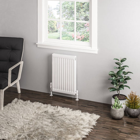 Modern white vertical radiator in stylish living room with wood flooring and houseplants