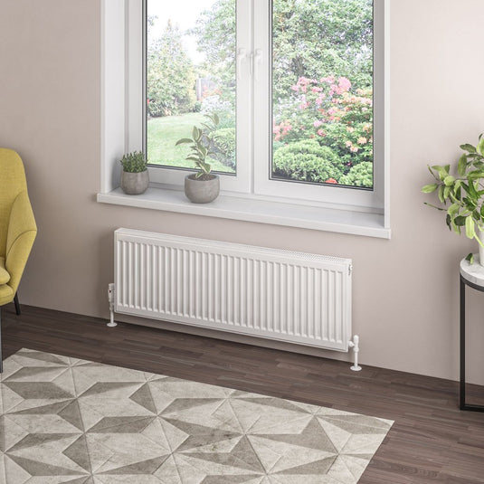 Modern white horizontal radiator under window in stylish living room with geometric rug