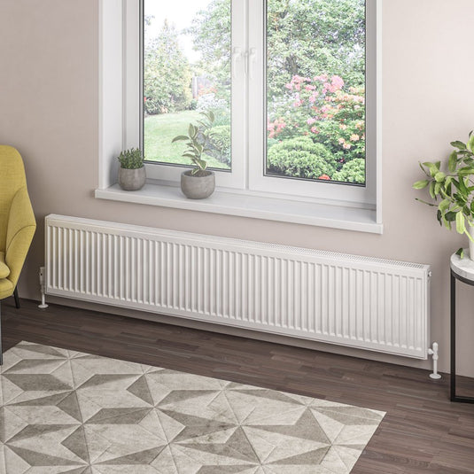 Modern white panel radiator under window in stylish living room with indoor plants