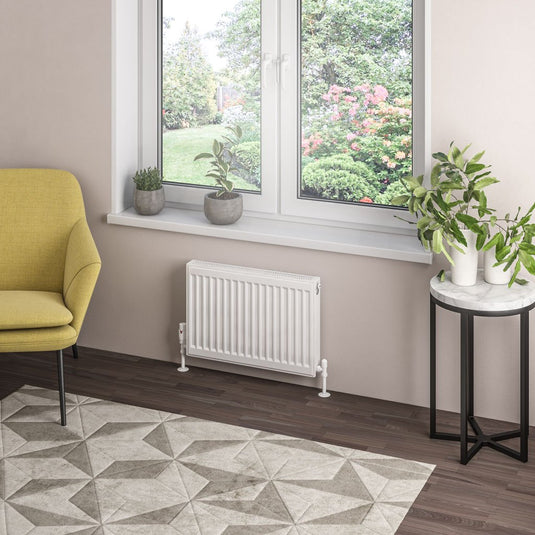 Modern living room with compact white radiator, geometric rug, houseplants, yellow chair, large window