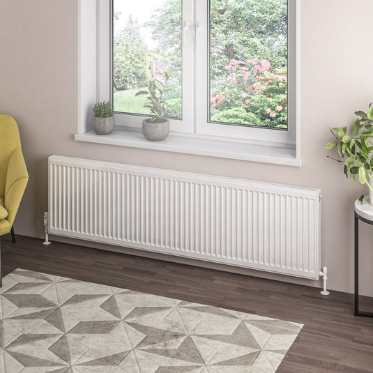 Modern horizontal white radiator under window in contemporary living room with indoor plants