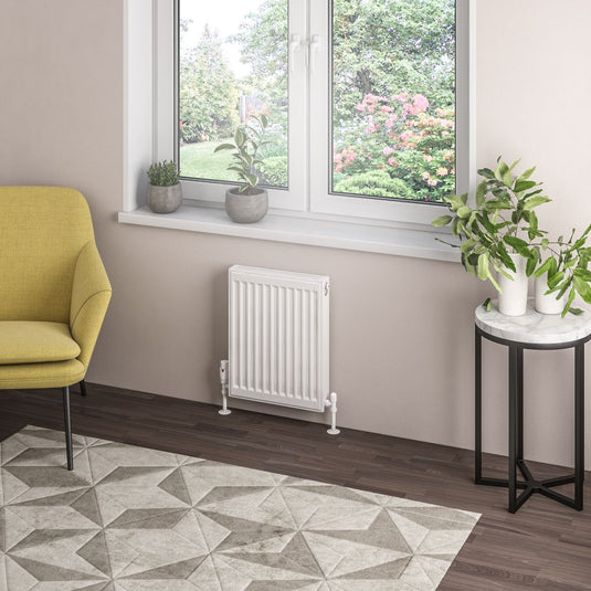 Modern white panel radiator under a window in a stylish living room with plants and armchair