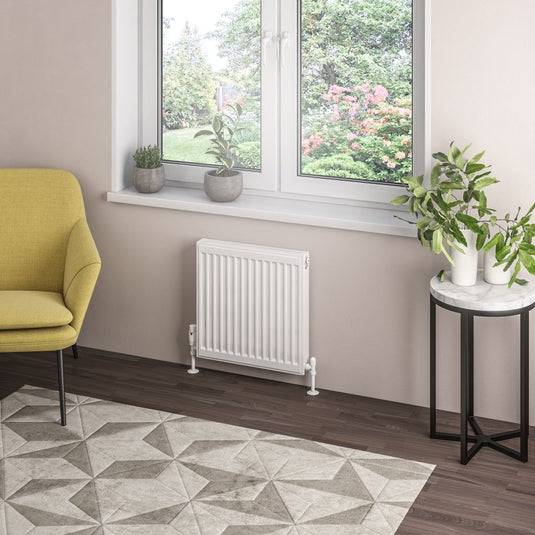 Modern bathroom with compact white radiator under window, indoor plants, and geometric rug