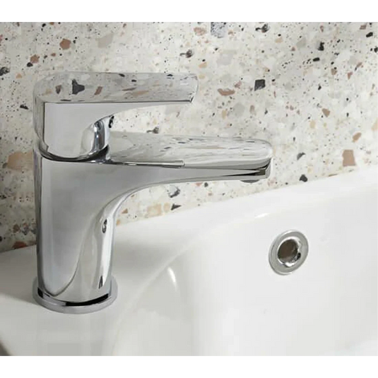 Modern chrome mini basin mixer tap with click waste installed on white bathroom sink