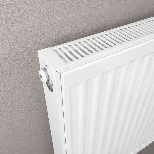 Modern white panel radiator mounted on a grey wall, close-up of top vent and control valve.