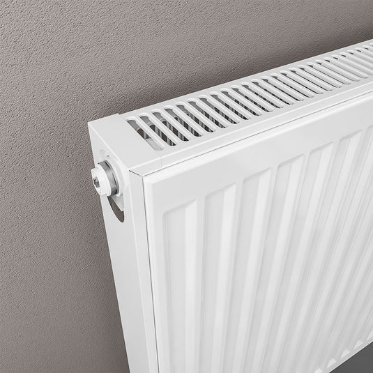Modern white panel radiator mounted on a grey bathroom wall