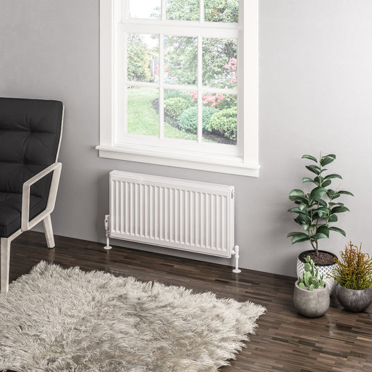 Modern white radiator under window in contemporary living room with plants and rug