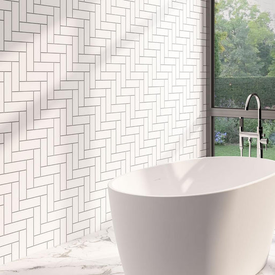 Modern bathroom with white herringbone wall tiles, freestanding bathtub, and large window