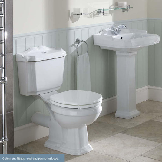Traditional white ceramic toilet cistern and pedestal basin in a classic bathroom setting