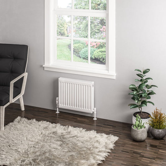 Modern white panel radiator under window in a stylish living room with plants and rug