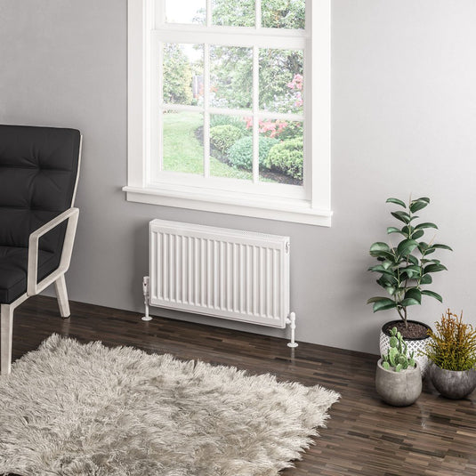 Modern white radiator under window in stylish living room with indoor plants and shag rug