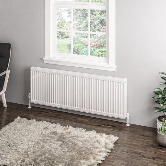 Modern white panel radiator under window in contemporary living room with shaggy rug and plants