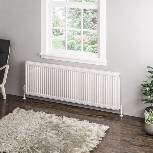 Modern white panel radiator under window in contemporary bathroom with grey walls and wood floor