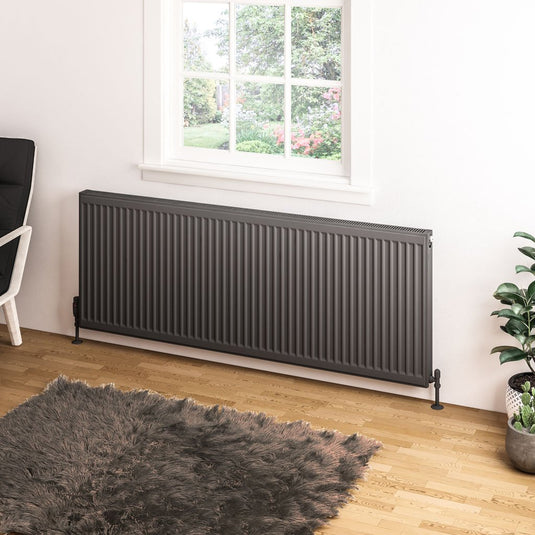 Modern anthracite horizontal radiator under window in cozy living room with wooden floor