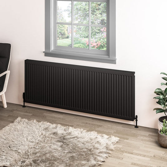 Modern black horizontal radiator under window in stylish living room with wooden floor