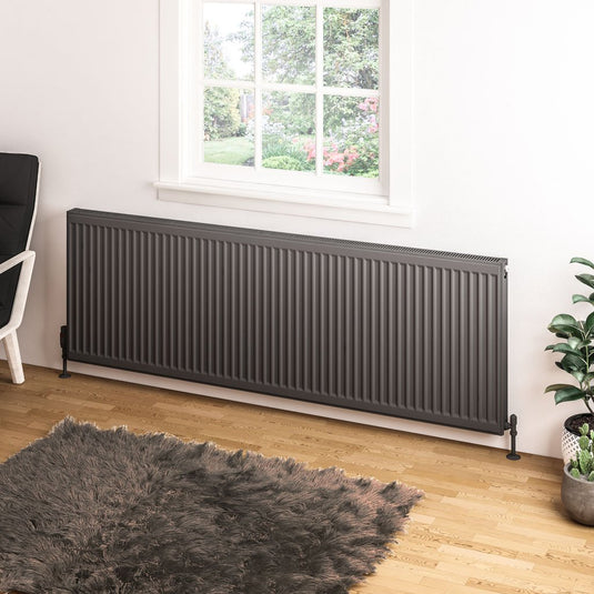 Modern anthracite horizontal radiator in a bright living room with wooden floor and rug