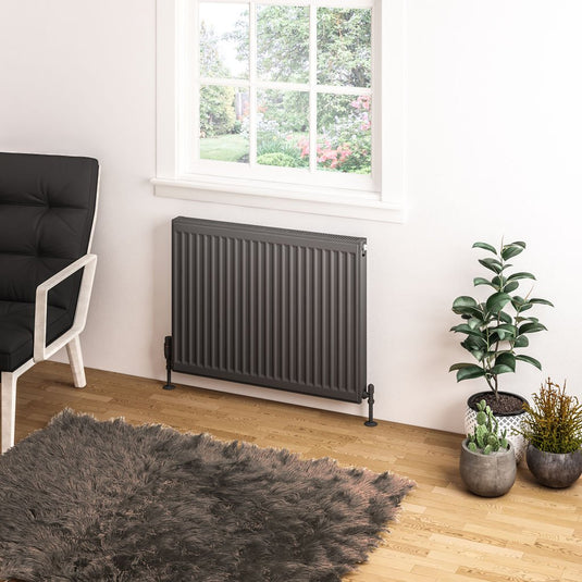 Modern vertical panel radiator under window in bright living room with plants and shaggy rug