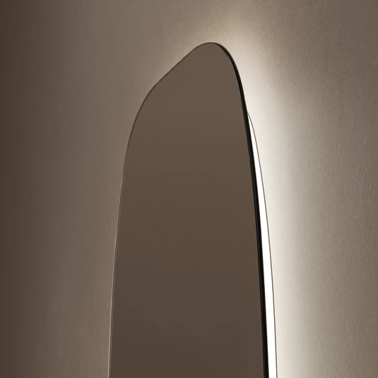 Modern rectangular barrel bathroom mirror with rounded edges and soft backlighting on wall